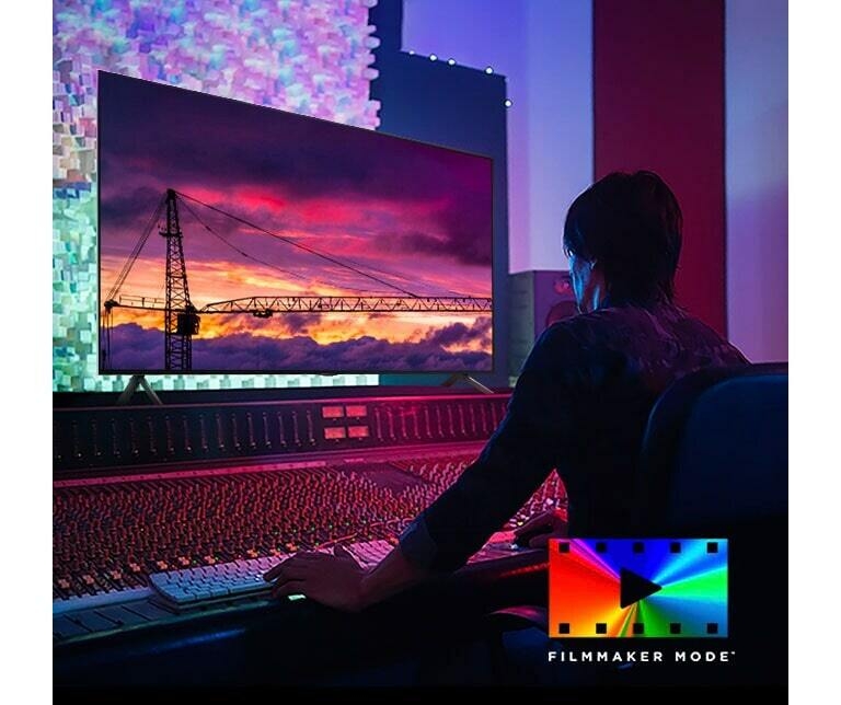 Homme dans un studio de montage sombre regardant un téléviseur LG qui montre le coucher de soleil. En bas à droite de l'image se trouve le logo FILMMAKER Mode.